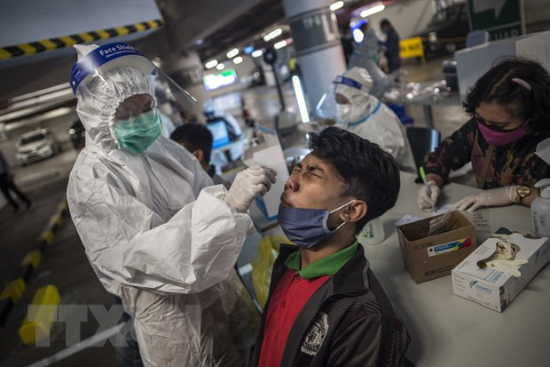 Nhân viên y tế lấy mẫu xét nghiệm COVID-19 cho người dân tại Surabaya, Indonesia ngày 17/6/2021. (Ảnh: AFP/TTXVN)