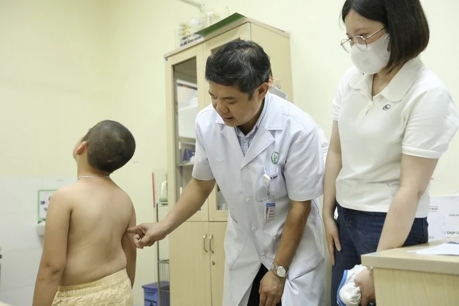 Bác sỹ khám, tư vấn cho bệnh nhi cong vẹo cột sống. (Ảnh: Minh Quyết/TTXVN)